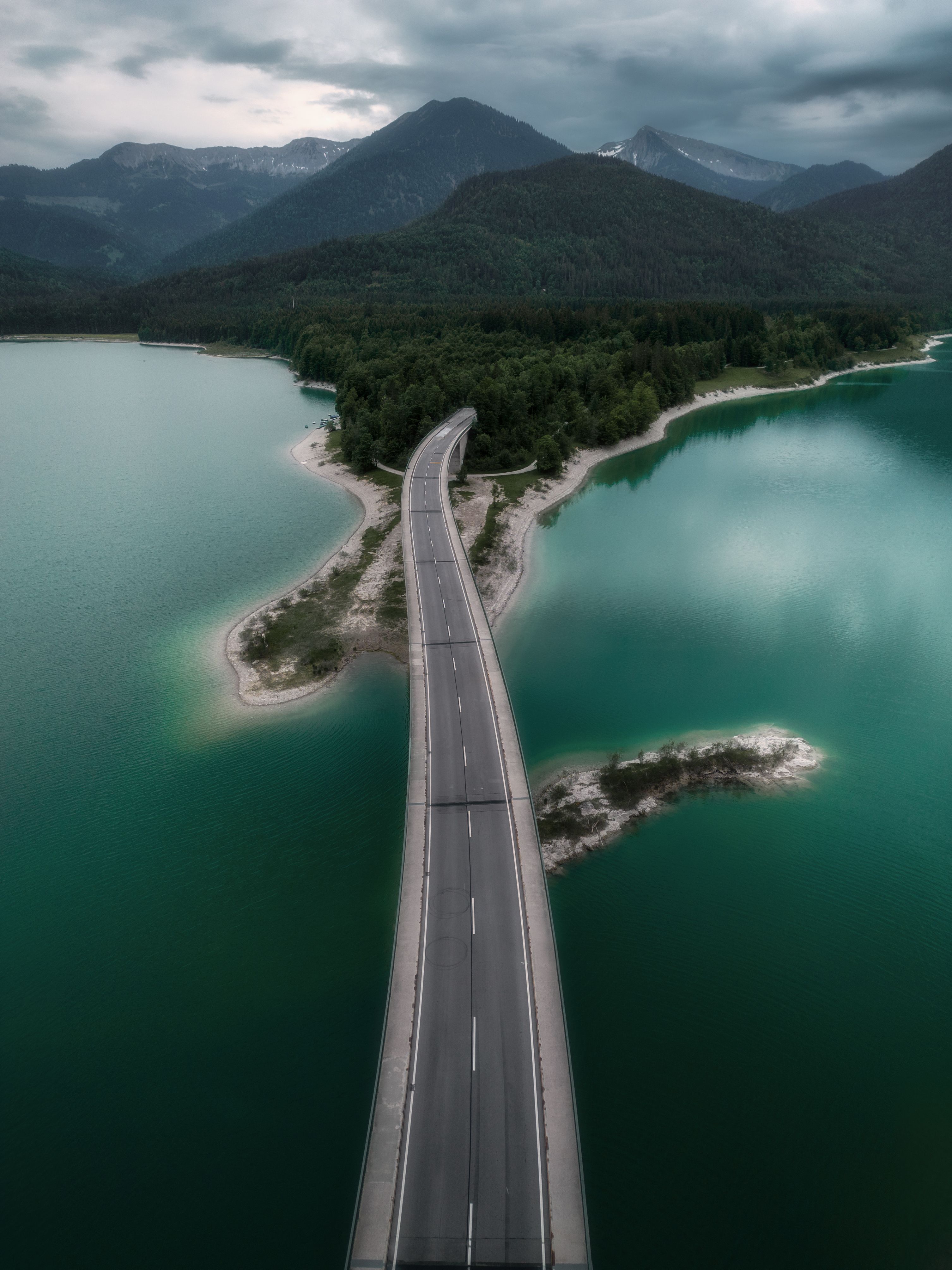 Aerial view of a bridge crossing water through mountainous landscape