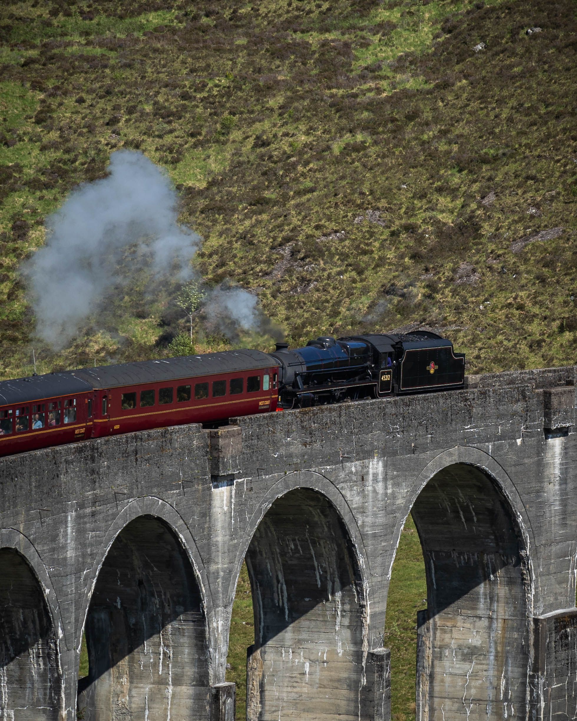 Railway train crossing a masonry viaduct in open landscape